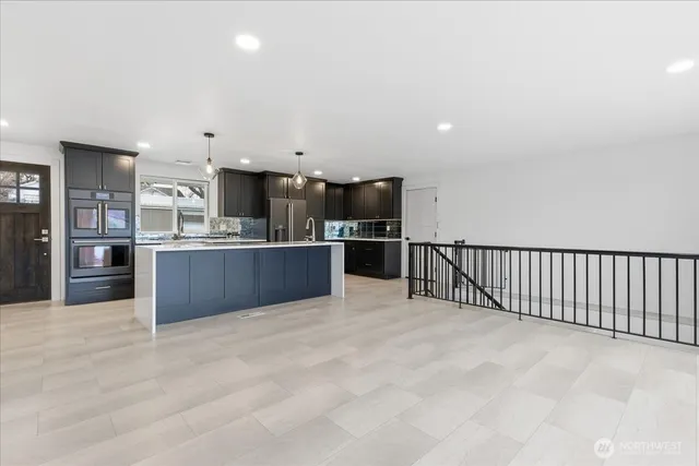 a view of kitchen with kitchen island stainless steel appliances cabinets and living room view