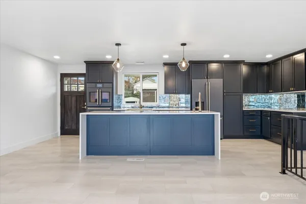 a large kitchen with kitchen island a large counter top stainless steel appliances and cabinets