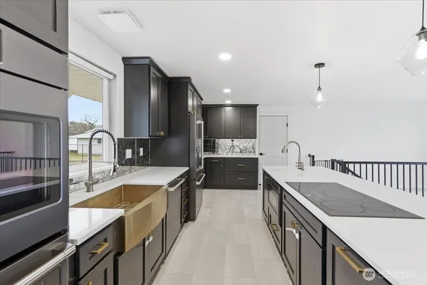 a large kitchen with stainless steel appliances granite countertop a sink a stove and a refrigerator