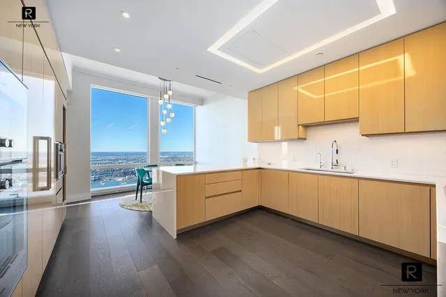 a kitchen with stainless steel appliances a stove top oven a sink a refrigerator white cabinets and wooden floor