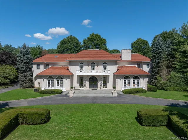 a front view of a house with garden and trees