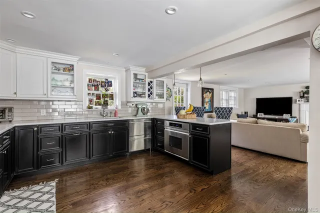 a large kitchen with a stove top oven a sink dishwasher a dining table and chairs with wooden floor