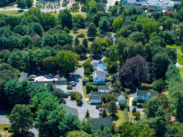 an aerial view of a house with a yard and covered with trees
