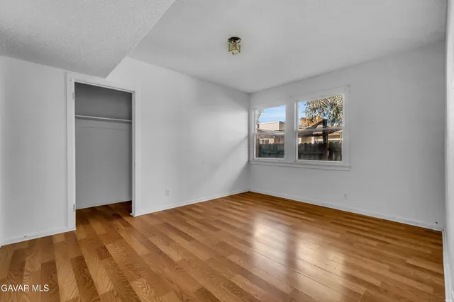 a view of empty room with wooden floor and fan