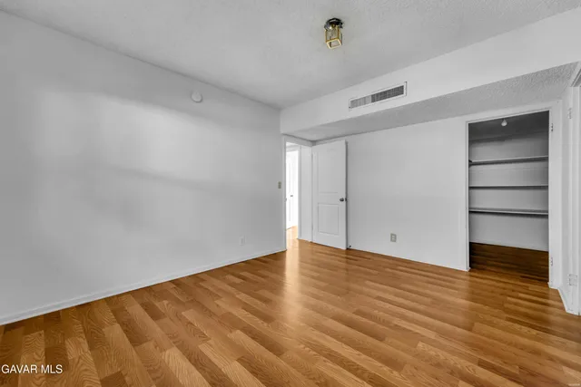 a view of an empty room with wooden floor and closet