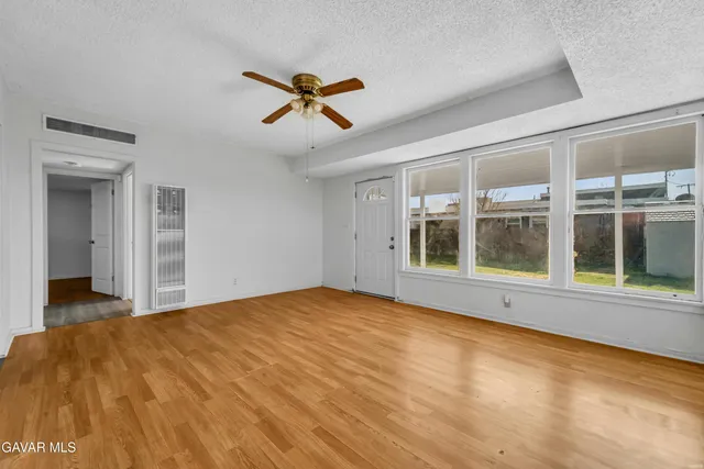 a view of an empty room with a window and wooden floor