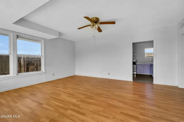 a view of empty room with wooden floor and ceiling fan