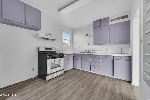 a kitchen with sink a stove and white cabinets