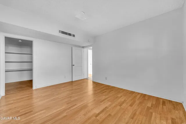 a view of an empty room with wooden floor and closet