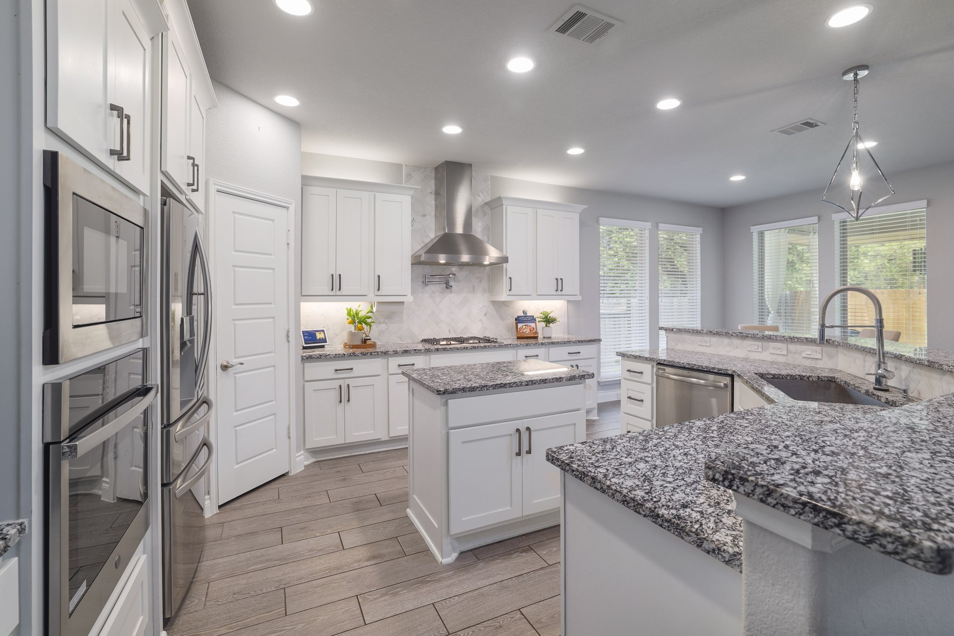 1513 Lakeside Ranch Road Georgetown, TX 78633 - Photo 14 of 40 Kitchen with wood finish floors, stainless steel appliances, white cabinetry, backsplash, and decorative light fixtures