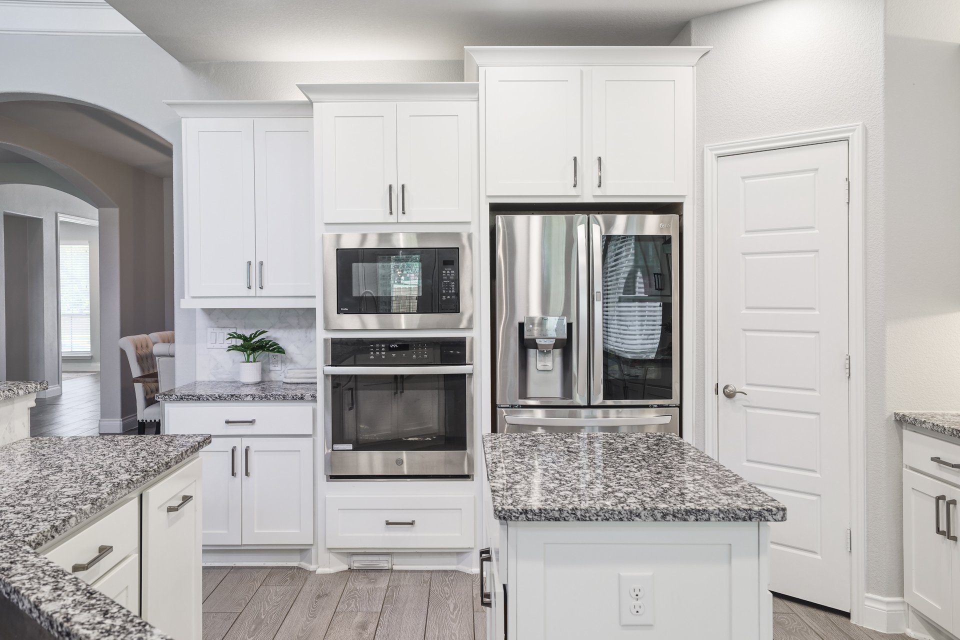 1513 Lakeside Ranch Road Georgetown, TX 78633 - Photo 16 of 40 Kitchen featuring stainless steel appliances, dark stone countertops, light wood finished floors, white cabinetry, and arched walkways