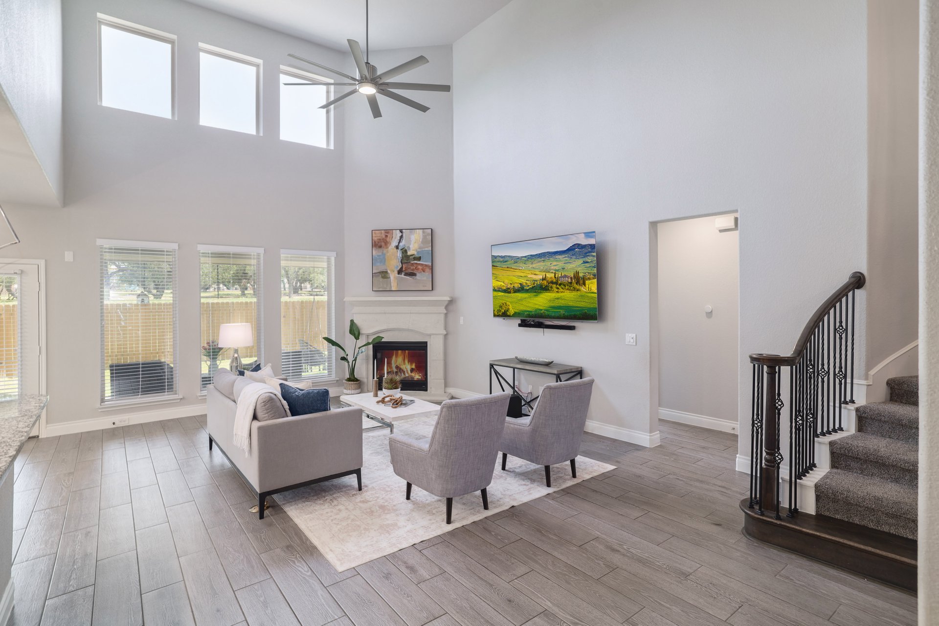 1513 Lakeside Ranch Road Georgetown, TX 78633 - Photo 9 of 40 Living room featuring light wood-style flooring, a lit fireplace, ceiling fan, and a high ceiling
