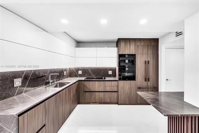 a kitchen with stainless steel appliances kitchen island granite countertop a refrigerator a sink and wooden cabinets