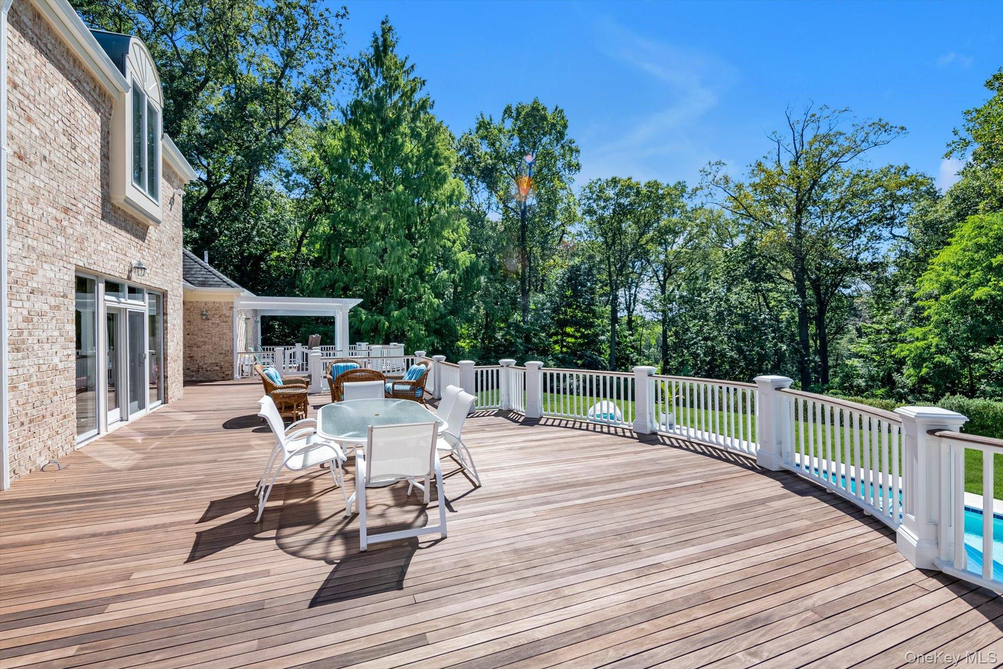 12 Overlook Court Locust Valley, NY 11560 - Photo 40 of 49 a view of a patio with dining table and chairs with wooden floor and fence