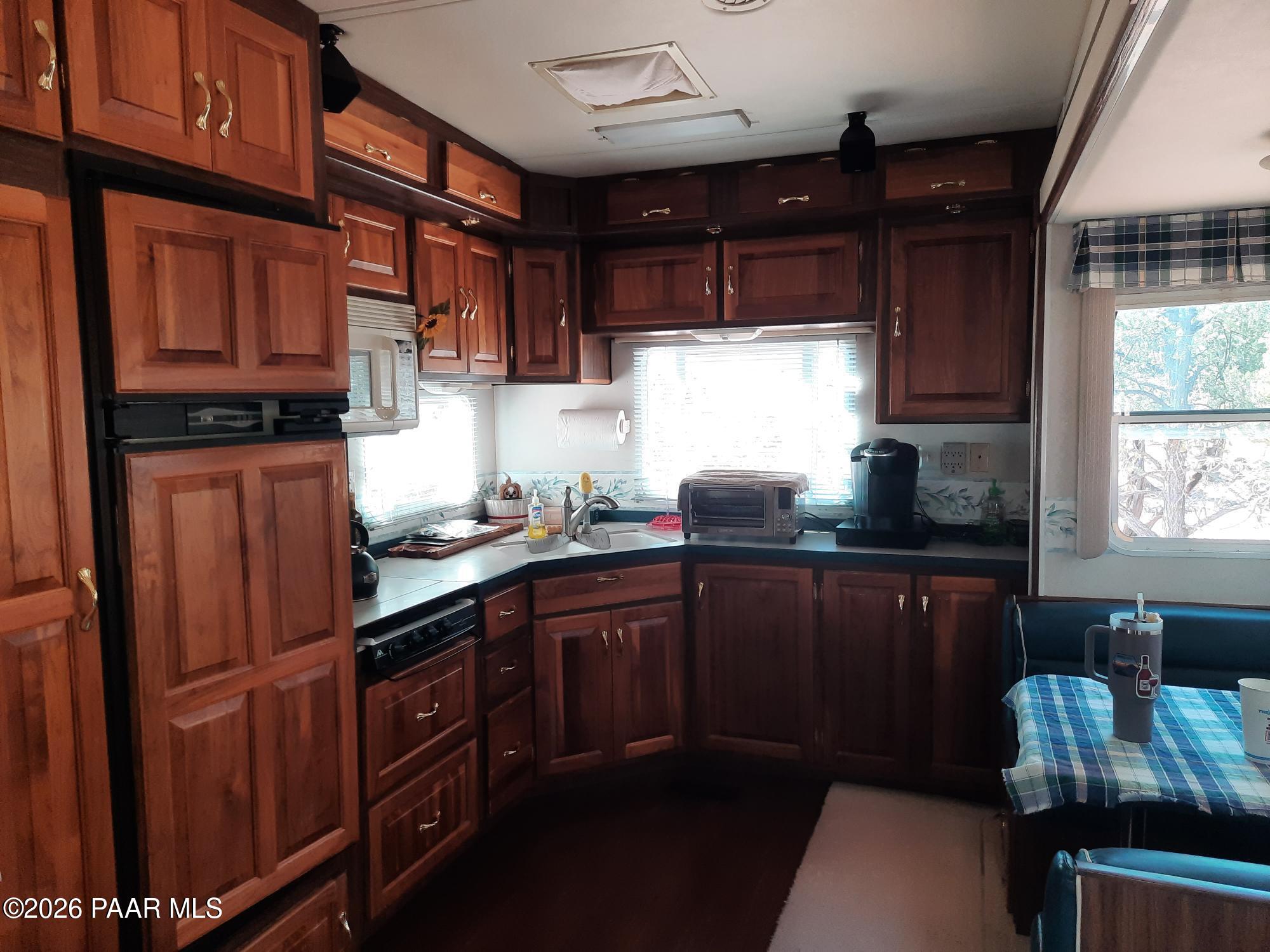 261 East W Titan Ranch Road Seligman, AZ 86337 - Photo 5 of 24 a kitchen with stainless steel appliances granite countertop wooden cabinets a refrigerator a sink a stove a dining table and chairs