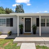 a view of a house with potted plants and a bench