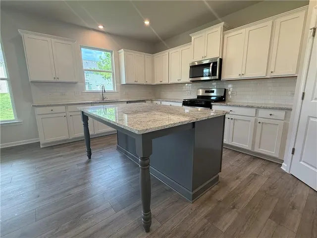 a kitchen with stainless steel appliances granite countertop a stove a sink dishwasher and a microwave oven with wooden floor