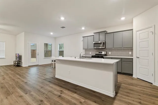 a kitchen with stainless steel appliances granite countertop a stove top oven a sink and white cabinets