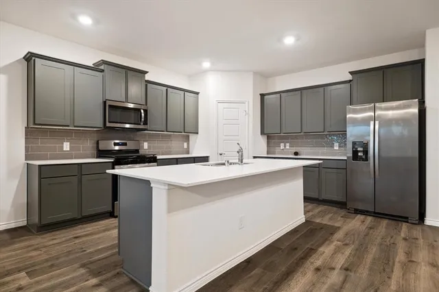 a kitchen with kitchen island a sink stainless steel appliances and cabinets