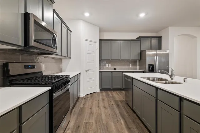 a kitchen with stainless steel appliances a sink dishwasher a stove top oven a refrigerator with island and chairs