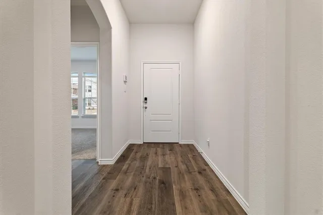 a view of a hallway with wooden floor and a bathroom