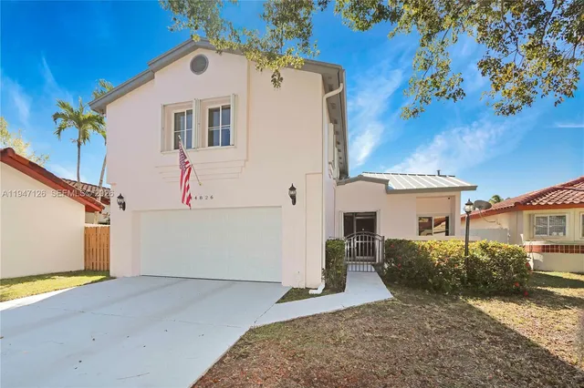 a view of a white house with a yard and garage