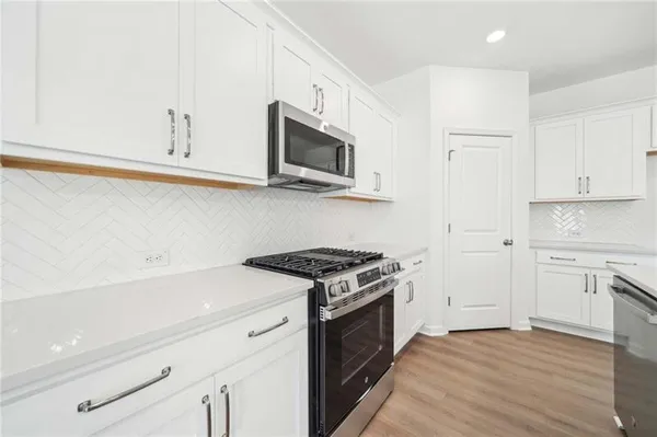a kitchen with stainless steel appliances white cabinets and a stove top oven