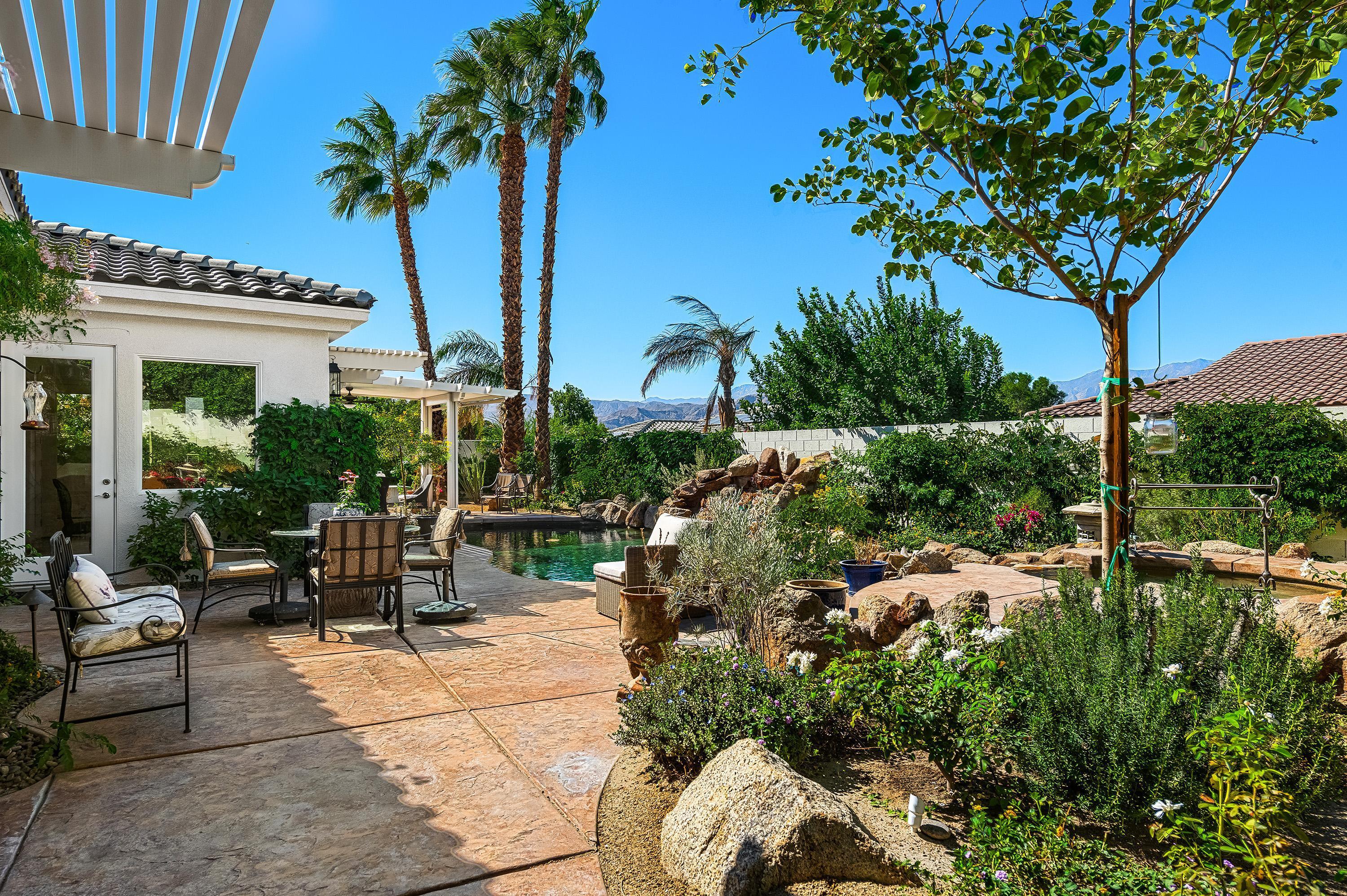 3 Trafalgar Rancho Mirage, CA 92270 - Photo 25 of 42 a view of a patio with couches and a table and chairs under an umbrella