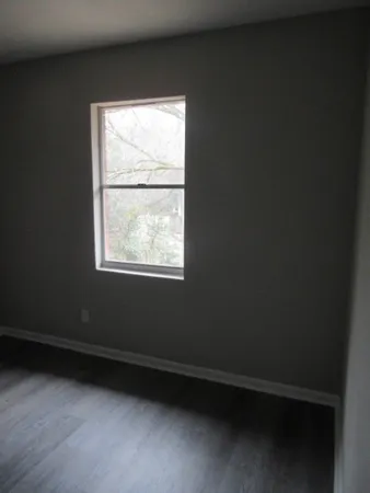 a view of an empty room with wooden floor and closet