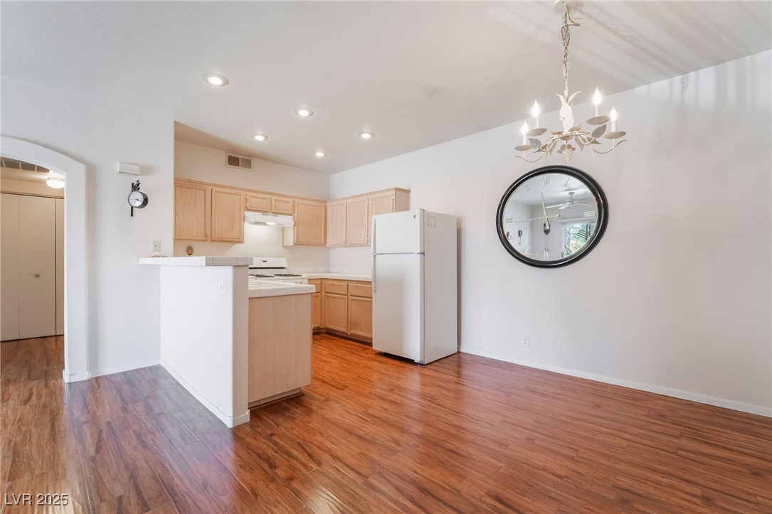 2201 Ramsgate Drive, Unit 823 Henderson, NV 89074 - Photo 6 of 31 Kitchen featuring white appliances, light brown cabinets, a peninsula, light countertops, and under cabinet range hood