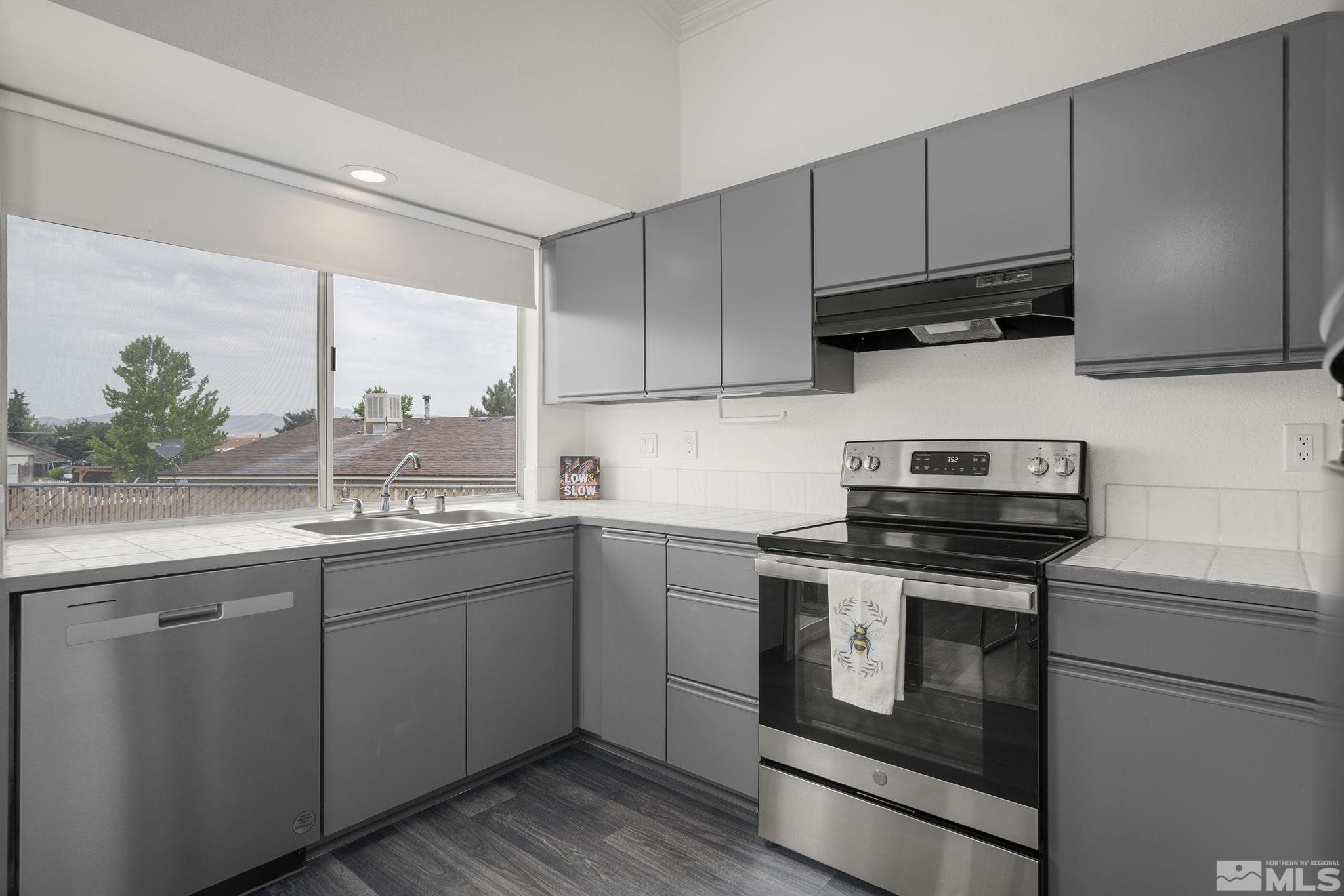 6885 Flower Street Reno, NV 89506 - Photo 8 of 21 a kitchen with stainless steel appliances granite countertop a sink a stove and a microwave