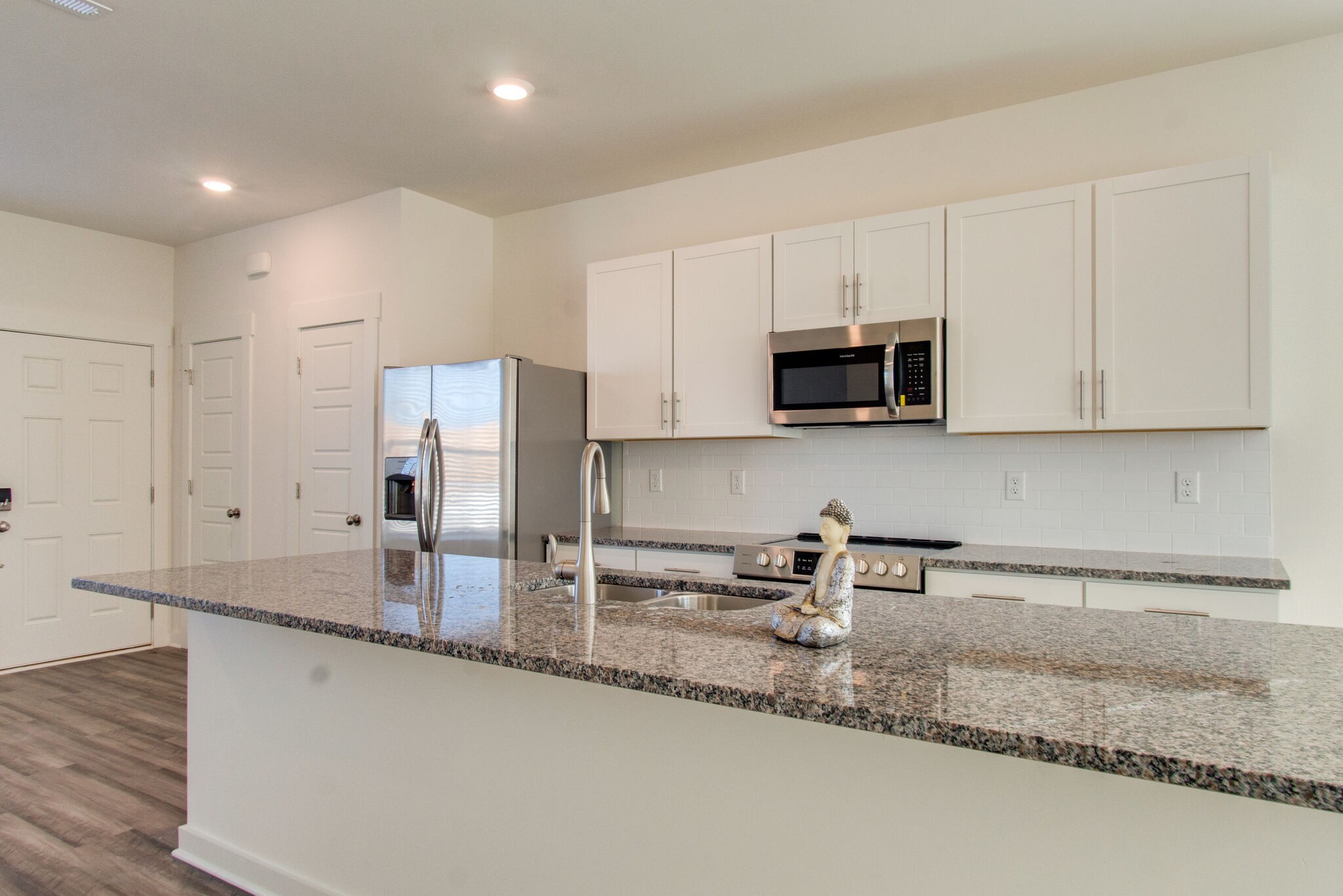 1703 Frodo Way Murfreesboro, TN 37128 - Photo 5 of 25 a kitchen with stainless steel appliances granite countertop a sink a microwave a refrigerator and white cabinets with wooden floor