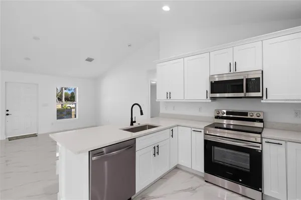 a kitchen with white cabinets and stainless steel appliances
