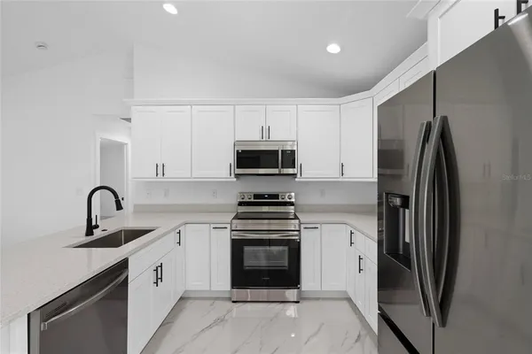 a kitchen with granite countertop a refrigerator and a stove top oven