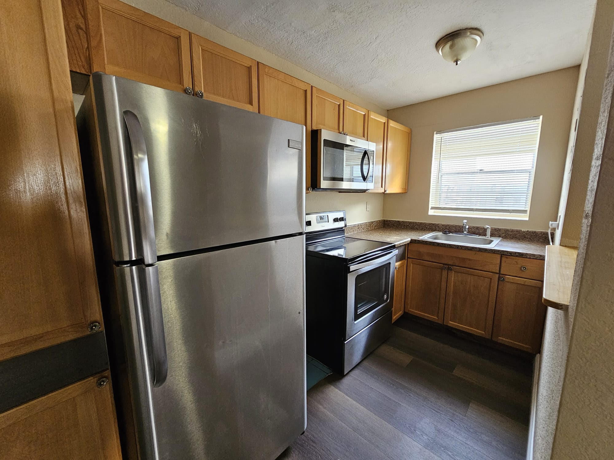 a kitchen with stainless steel appliances a refrigerator a sink a stove a microwave and cabinets