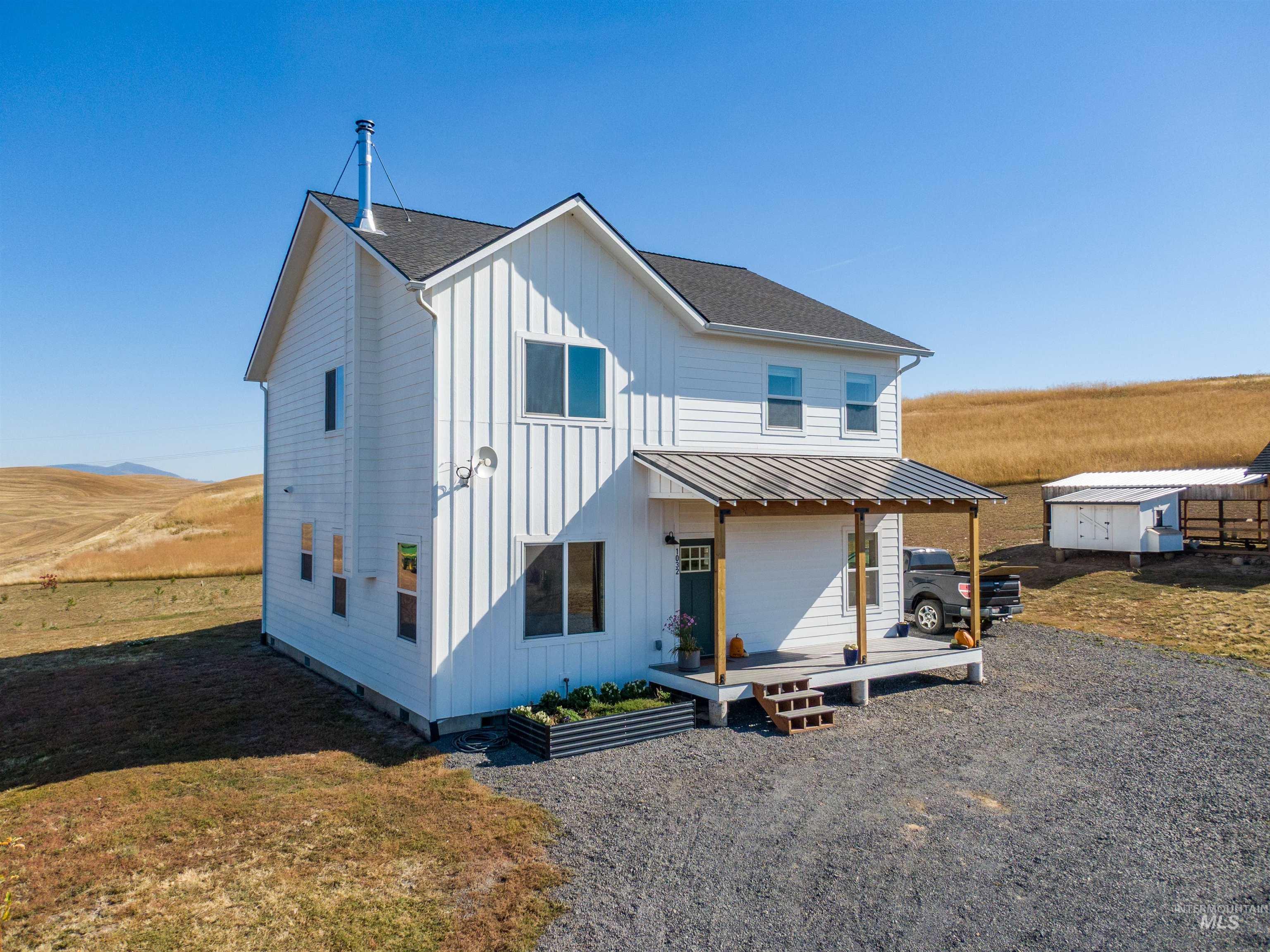 1032 Duffield Flat Road Potlatch, ID 83855 - Photo 41 of 50 White vertical siding exterior with a covered front porch, dark shingle roof, and gravel driveway
