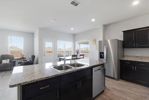 a kitchen with stainless steel appliances granite countertop a sink a stove a refrigerator a washer and dryer
