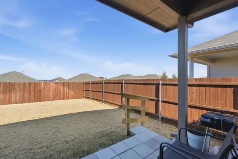 a view of a backyard with wooden floor and iron fence