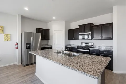 a kitchen with stainless steel appliances granite countertop a sink stove microwave and refrigerator