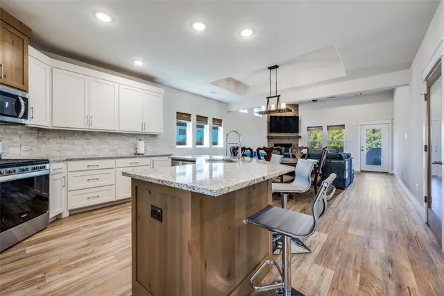 a kitchen with stainless steel appliances granite countertop a stove top oven a sink dishwasher and a microwave oven with wooden floor