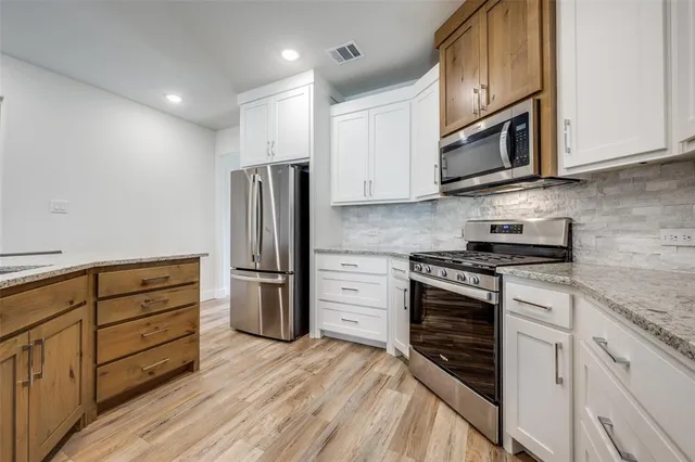 a kitchen with granite countertop white cabinets and stainless steel appliances