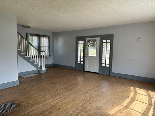 a view of an empty room with window and wooden floor