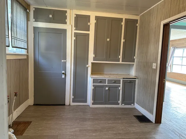 an empty room with wooden floor cabinet and windows