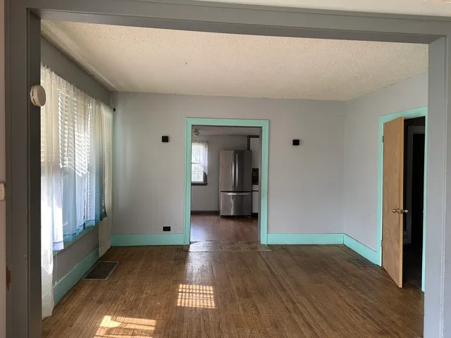 a view of a hallway with wooden floor and a living room