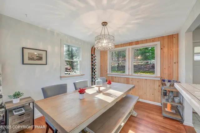 a kitchen with a refrigerator a sink dishwasher a dining table and chairs with wooden floor