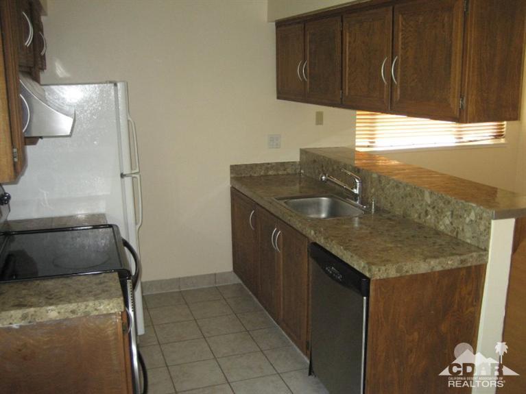 72711 Eagle Road, Unit 4 Palm Desert, CA 92260 - Photo 6 of 29 a kitchen with a sink a refrigerator and cabinets