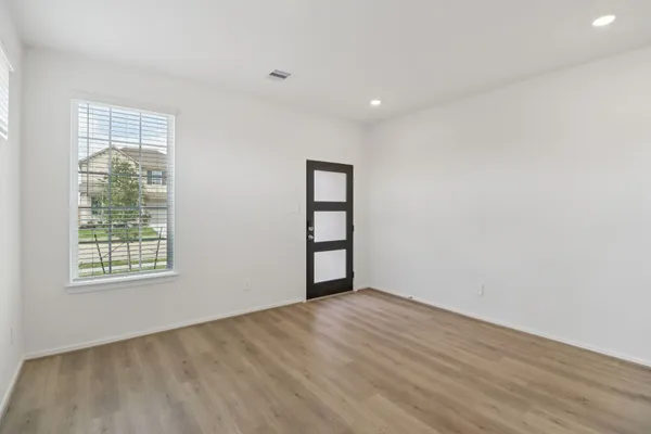 an empty room with wooden floor and windows