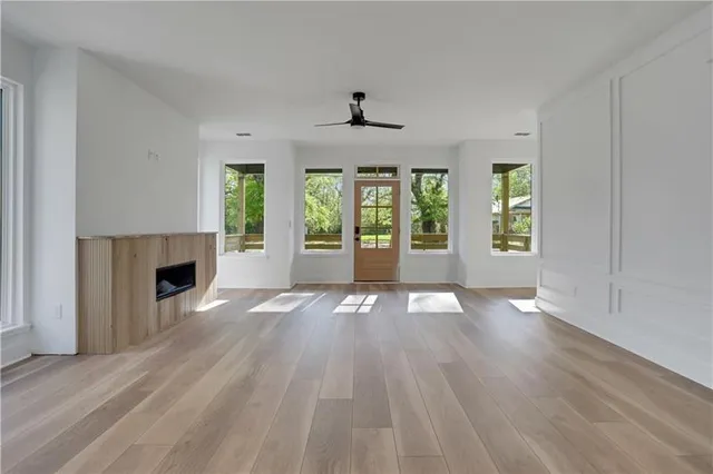 an empty room with wooden floor fireplace and windows