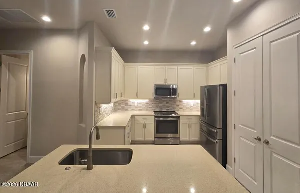 a kitchen with stainless steel appliances granite countertop a sink and a refrigerator