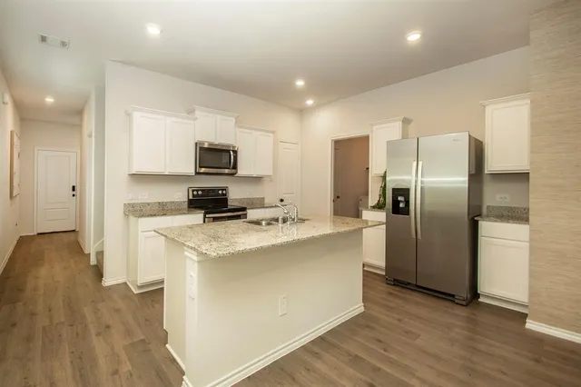 a kitchen with stainless steel appliances granite countertop a sink a stove a refrigerator and a microwave